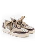 A beige and brown sneaker with a lace-up closure, featuring a low heel and a round toe shape.