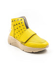 A yellow high-top sneaker with a velcro strap, metal eyelets, and a beige sole.