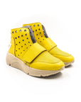 A yellow high-top sneaker with a velcro strap, metal eyelets, and a beige sole.