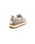 A beige sneaker with a Velcro strap and a low heel, suitable for casual wear.