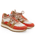 A women's sneaker with a beige, red, and white color scheme, featuring a lace-up closure and a flat sole.