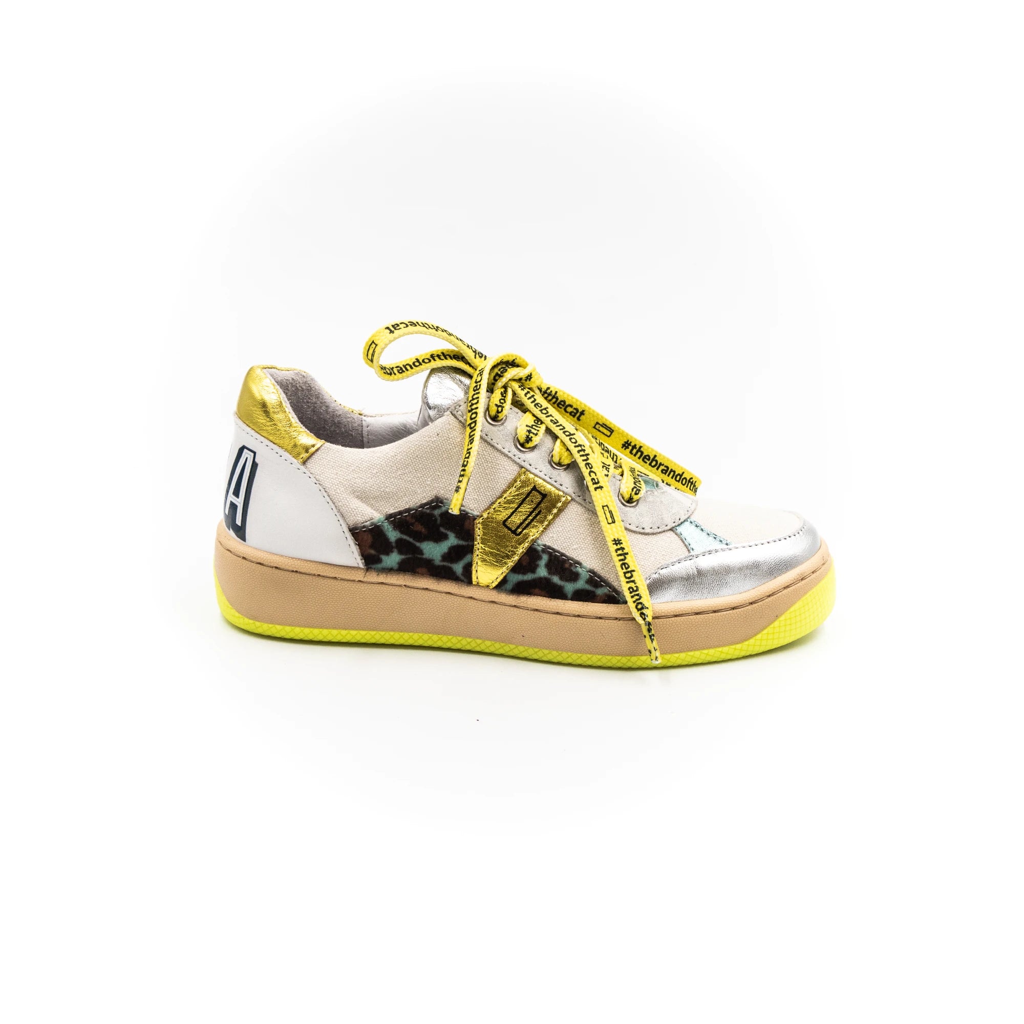 A sneaker with silver upper, yellow laces, and a beige sole.