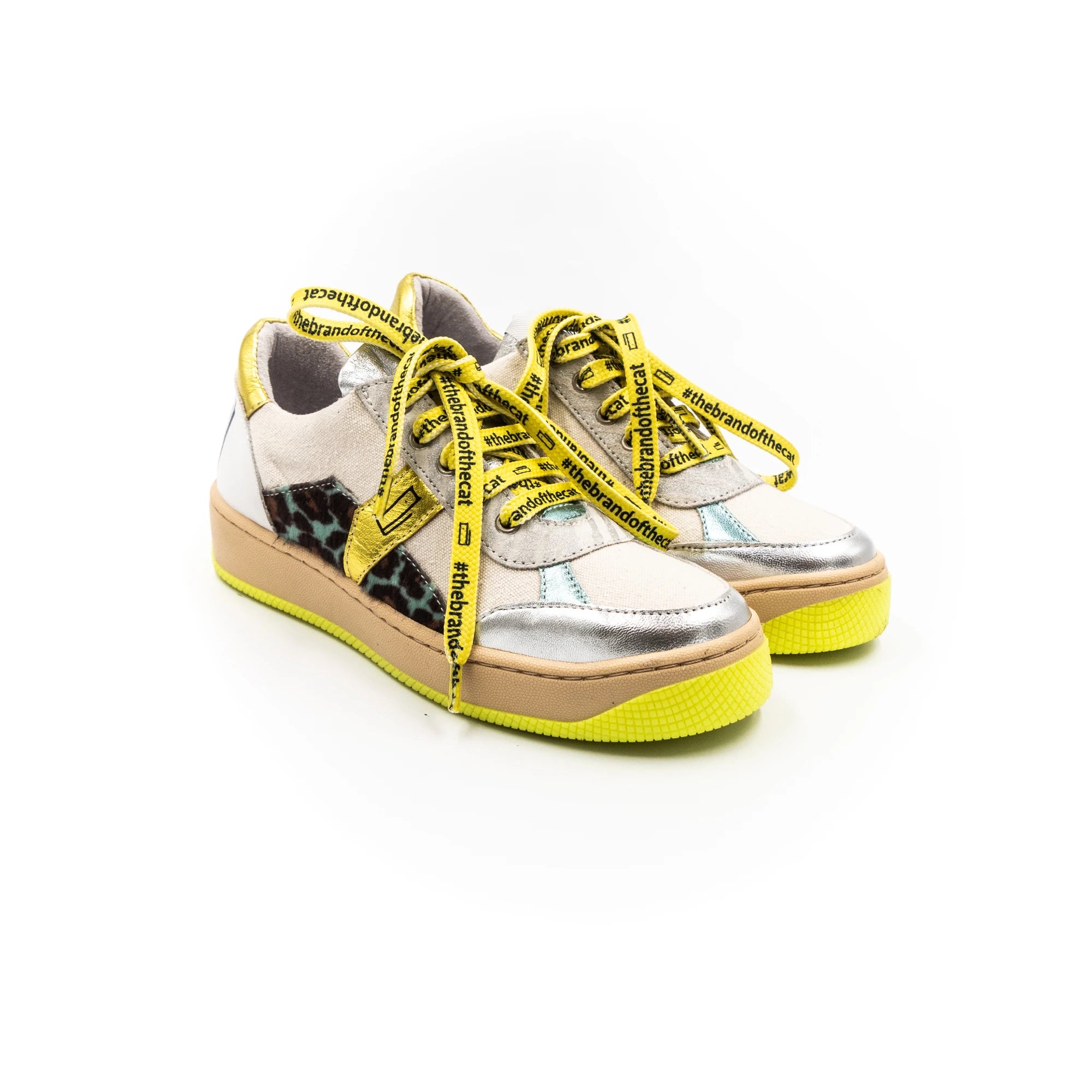 A sneaker with silver upper, yellow laces, and a beige sole.