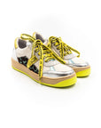 A sneaker with silver upper, yellow laces, and a beige sole.